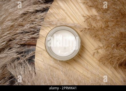 Vaso panna aperto su foglia di palma secca vicino all'erba di pampas. Trucco cosmetico Foto Stock