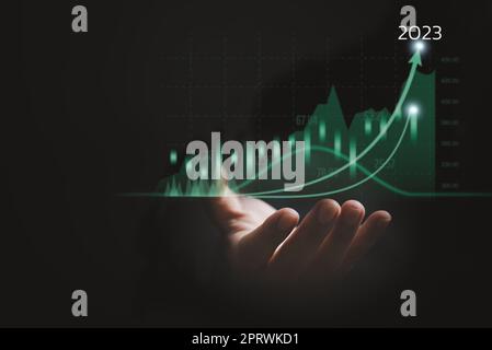 Business man holding grafico dei dati di crescita freccia con 2023 grafico di bilancio, business grafico aziendale futuro successo sviluppo e strategia di motivazione Foto Stock