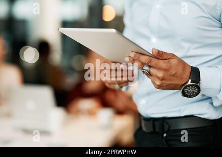 Lo strumento perfetto per la gestione dei progetti. Un uomo d'affari che utilizza un tablet digitale durante una riunione di gruppo in un ufficio moderno. Foto Stock