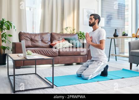 Non ho mai saltato una sessione da quando mi sono iscritto. Un uomo che usa il suo laptop mentre praticava yoga a casa. Foto Stock