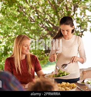 Dare a mamma un po' di più. Una donna e sua figlia che si godono un pasto in famiglia all'aperto. Foto Stock