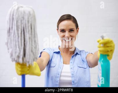 Lascia sporcare le mani. Una donna sorridente che tiene fuori un mop e spruzzare il flacone. Foto Stock