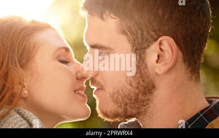 Lets get lost in our lips. Una giovane coppia felice che condivide un bacio all'aperto. Foto Stock