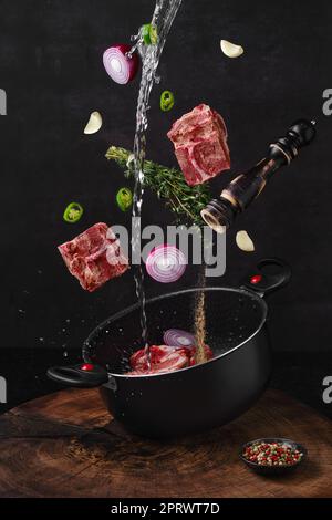 Ossa di manzo tritate che cadono in casseruola con ingredienti per brodo di brodo Foto Stock