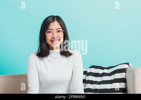 donna che indossa occhiali da vista seduta sul divano Foto Stock