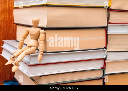 Manichino in legno seduto sulla libreria Foto Stock