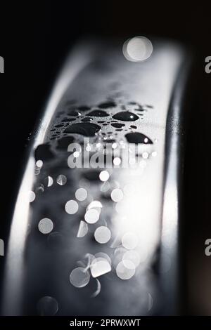 Gocce d'acqua Abstract e con sfondo sfocato brilla su una superficie metallica di una sedia. Macro shot astratto Foto Stock