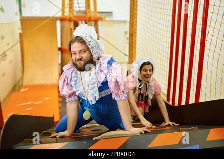 Cute uomo e donna come bambino arrampicata in labirinto sala giochi Foto Stock