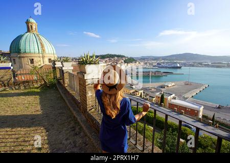 Turismo ad Ancona. Vista posteriore di una donna viaggiatore che gode di una vista sulla città di Ancona e sul porto dalla terrazza, Marche, Italia. Foto Stock