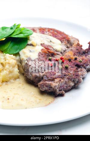 bistecca di manzo con salsa, purè di patate e foglie di spinaci Foto Stock