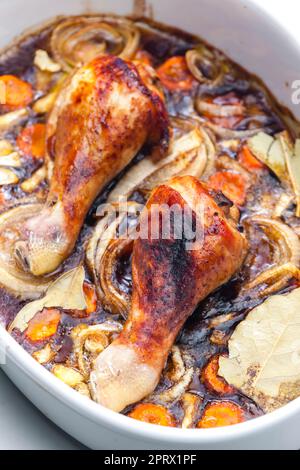 cosce di pollo al forno con cipolla, carota e foglie di alloro Foto Stock