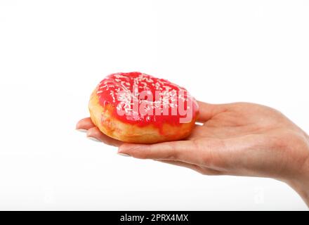 La mano della donna tiene la ciambella rossa sopra il bianco Foto Stock