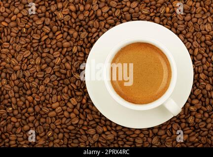 Tazza di espresso bianca su chicchi di caffè tostati Foto Stock