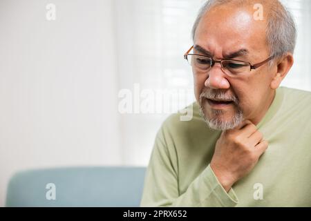 Pensione anziano sensazione di dolore usare le mani tenendo il collo e irritazione in gola, anziani hanno disfagia a causa di mangiare, asiatico vecchio doloroso Foto Stock