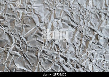 Sottile foglio stropicciato di alluminio stagnato argento sfondo con superficie lucida stropicciata per la texture Foto Stock