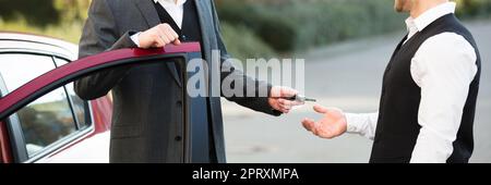 Servizio di parcheggio con parcheggiatore. In piedi vicino alla porta che dà la chiave Foto Stock