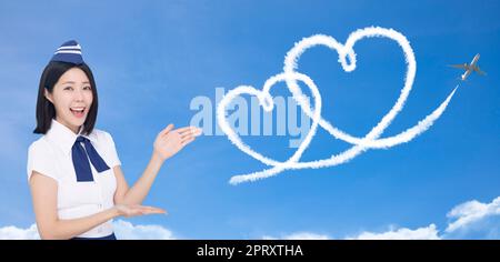 Bella stewardess che mostra l'amore e il concetto di viaggio di luna di miele su sfondo blu Foto Stock