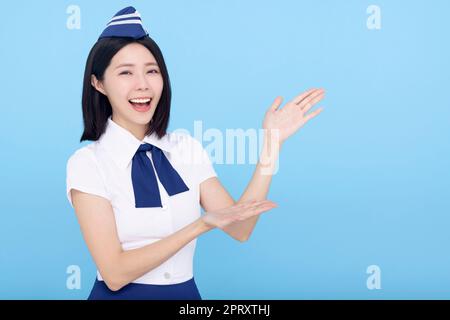 Bella stewardess che mostra qualcosa su sfondo blu Foto Stock