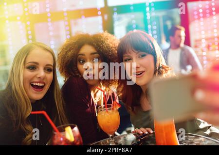 Circa ieri sera. giovani amici che scattano selfie mentre sorseggiano un drink a una festa Foto Stock