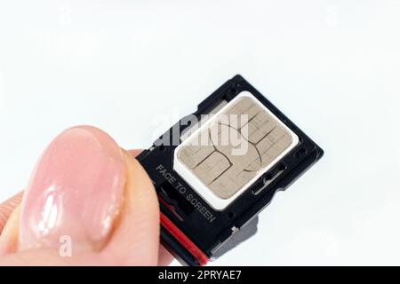 La donna inserisce la scheda sim del telefono nell'alloggiamento dal primo piano dello smartphone. Foto Stock