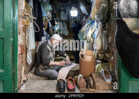 Calzolaio artigiano che taglia sottopiedi in pelle per la fabbricazione di pantofole. Foto Stock