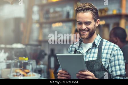 Restare al passo con le tendenze delle piccole e medie imprese con la tecnologia moderna. un giovane uomo che utilizza un tablet digitale nel negozio in cui lavora Foto Stock