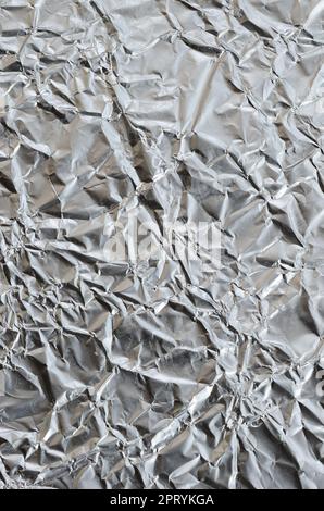 Sottile foglio stropicciato di alluminio stagnato argento sfondo con superficie lucida stropicciata per la texture Foto Stock