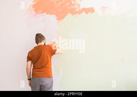 Giovane uomo con spatola e intonacatura di parete con stucco bianco fresco di finitura. Primo piano. Lavori di riparazione di casa. Spazio vuoto per il testo. Vista laterale Foto Stock