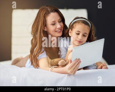 Connessione in più modi. Scatto completo di una madre e di sua figlia utilizzando un tablet digitale Foto Stock