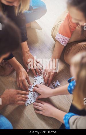 Il quadro completo sta lentamente arrivando. un gruppo di persone che costruiscono un puzzle insieme Foto Stock