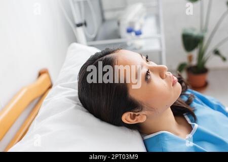 donna asiatica depressa sdraiata sul letto nel reparto dell'ospedale e guardando via, immagine di scorta Foto Stock