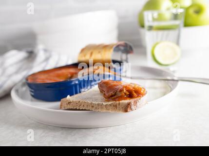 Aringa in scatola in salsa di pomodoro su una fetta di pane Foto Stock