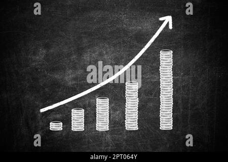 Concetto di aumento dello stipendio. Freccia su e monete impilate sulla lavagna Foto Stock