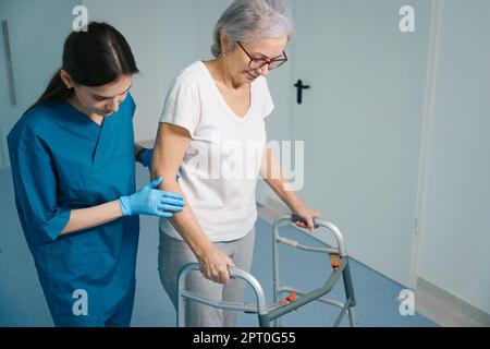 Un infermiere premuroso accompagna un paziente anziano in clinica Foto Stock