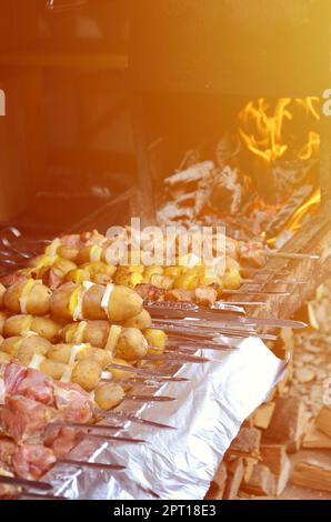 La carne cruda e le patate sono piantati su spiedini di metallo. Il processo di cottura shish kebab. Russo e ucraino cibo camp Foto Stock