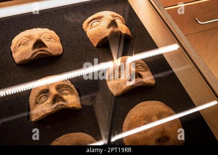 Málaga, Spagna -- maschere in argilla antiche in mostra in una cassa di vetro al Museo de Málaga Foto Stock