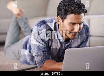 HES profondamente immerso nel mondo del web. Un giovane uomo che usa il suo notebook a casa Foto Stock