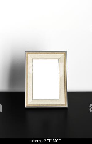 Telaio verticale Mockup in piedi su un tavolo di legno all'interno della sala d'ufficio su sfondo bianco parete Foto Stock