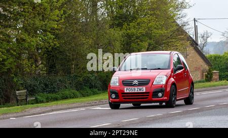 Bicester, Oxon, Regno Unito - Aprile 23rd 2023. 2009 rosso CITROEN C2 viaggiando su una strada di campagna inglese Foto Stock