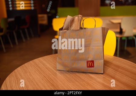 Valencia, Spagna - 16 ottobre 2022: Confezione sacchetto di carta design per il servizio di consegna di proprietà del fast food ristorante McDonalds su un tavolo al caffè della città Foto Stock