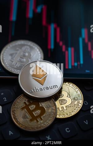 Stack o cumulo di oro varie criptovaluta vicino a un monitor con grafico a candela e calcolatrice digitale. Bitcoin, Ethereum, Cardano, Litecoin Foto Stock