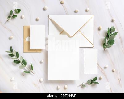 Carte e busta su un tavolo di marmo vicino a rami di eucalipto e ciottoli vista dall'alto, Mockup. Romantico appartamento con set di cancelleria per matrimoni. Minimo com Foto Stock