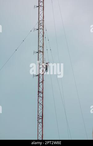 Gli uomini stanno salendo sull'antenna. Per installare il dispositivo Foto Stock