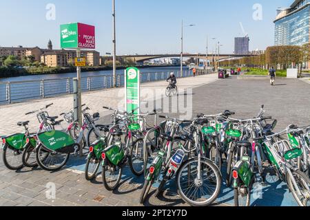 Stand per BICICLETTE pubbliche OVO a noleggio, sulla pista ciclabile del distretto di Anderston, accanto al fiume Clyde, vista ovest con il ponte Kingston in lontananza. Foto Stock