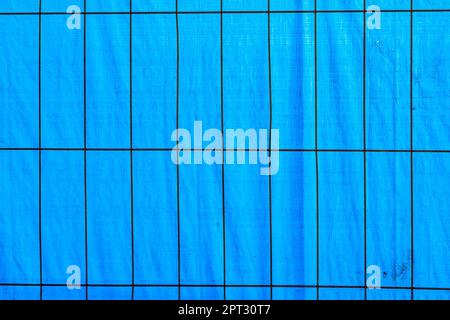sfondo di lamina di plastik blu con griglia metallica in primo piano per proteggere un cantiere Foto Stock