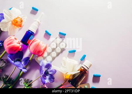 Allergia primaverile stagionale. Pillole e spray nasale piatto steso con fiori rosa viola. Trattamento allergico ai pollini. Vista dall'alto. Spazio Foto Stock