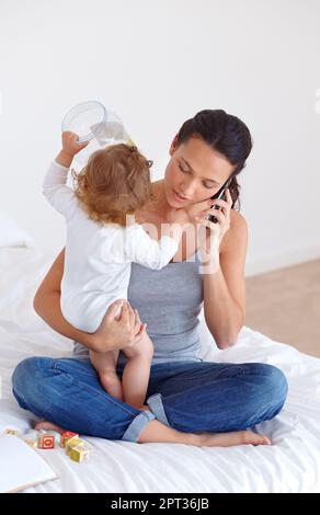 Cercando di equilibrare tutto - maternità. una bella giovane donna e il suo bambino a casa Foto Stock