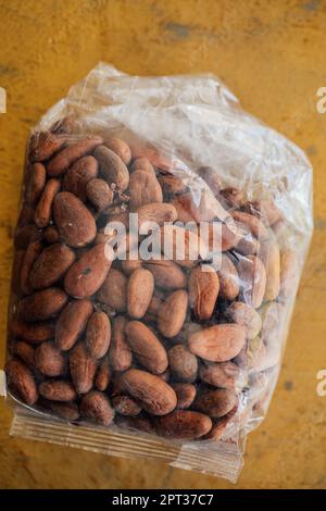 Sacchetto di plastica trasparente di cacao messicano, cacao in grani su fondo dorato Foto Stock