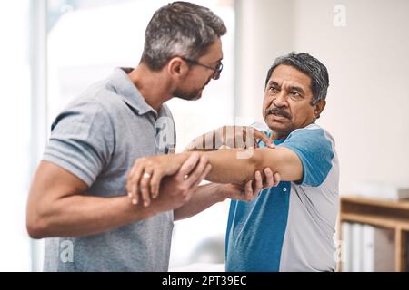 Questa è la zona im che sperimenta un certo dolore dentro. un uomo anziano che passa attraverso la riabilitazione con il suo fisioterapista Foto Stock