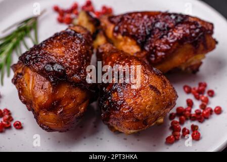 Deliziose cosce di pollo alla griglia con spezie ed erbe aromatiche in salsa teriyaki su fondo di cemento scuro Foto Stock